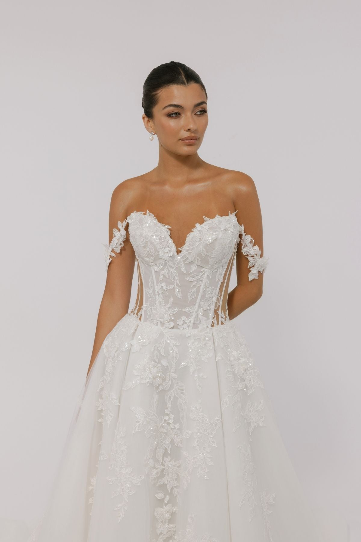 wedding dress featuring off the shoulder straps, sweetheart neckline, sheer boning on the sides, and floral lace A-line skirt 