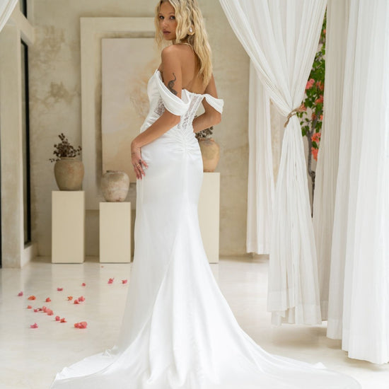 fitted wedding gown, with off the shoulder cap sleeves, and a tied ruched knot around the hips, high split. 