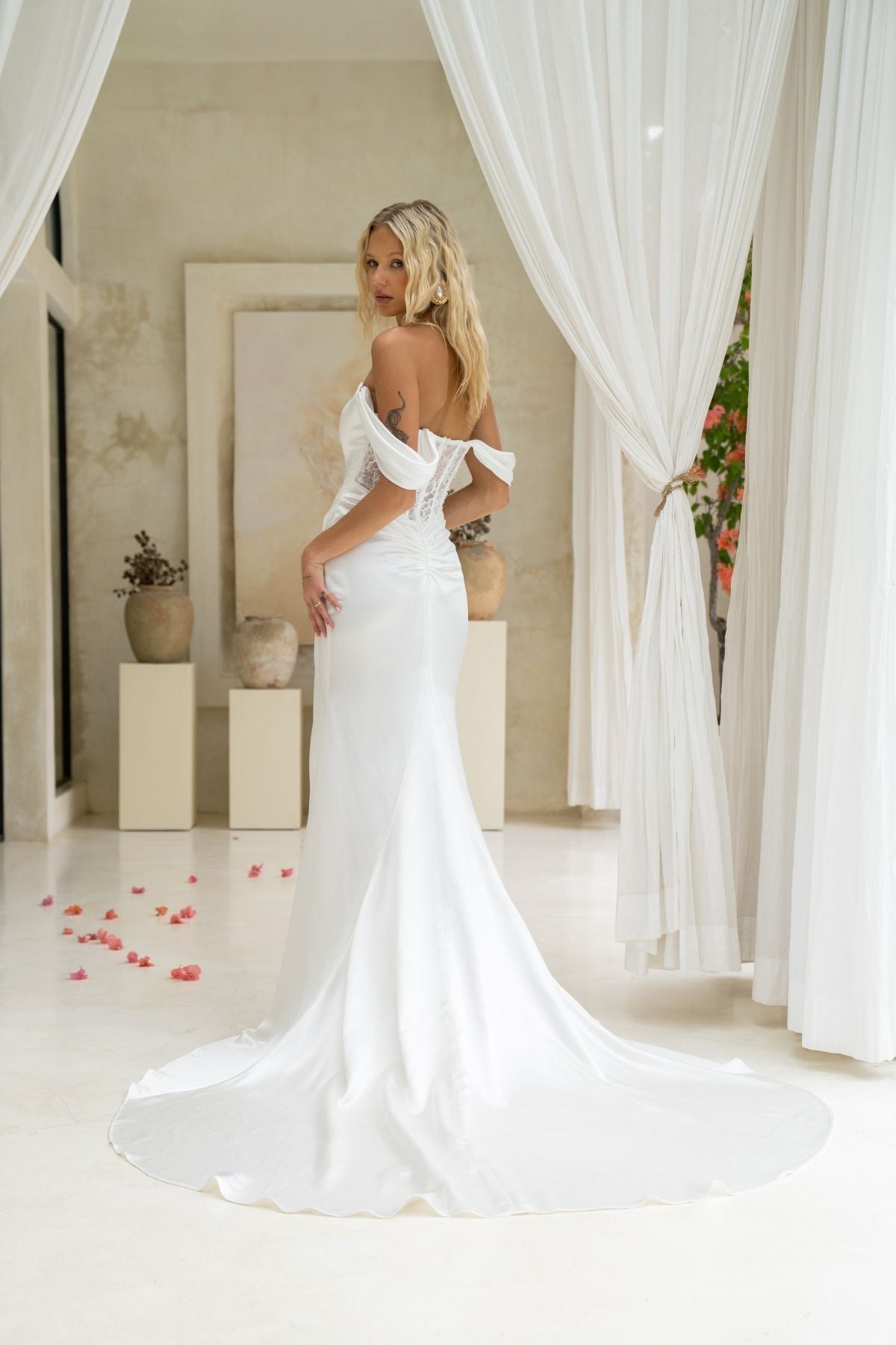 fitted wedding gown, with off the shoulder cap sleeves, and a tied ruched knot around the hips, high split. 