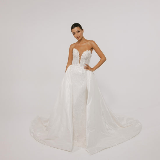 Fitted wedding gown with a deep v plunge, strapless neckline, beaded lace. With voluminous overskirt 