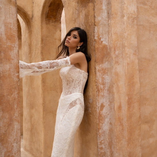 fitted lace wedding dress with basque waist, cat-eye neckline and side cut-outs. paired with fitted lace sleeves. 