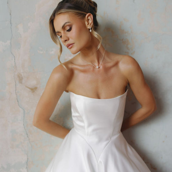 Strapless A-line satin wedding gown featuring cut drapes on the skirt 