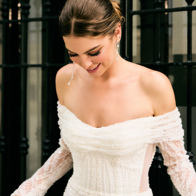 Close up of beaded bodice. Off-the-shoulder neckline with sheer sleeves and sheer mesh panels at waist. 