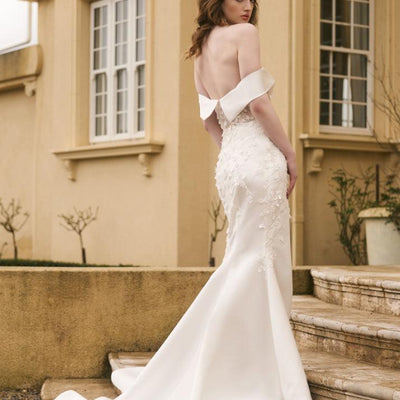 Back of Theia dress. Ivory off-shoulder band meets at centre back. 3D floral lace climbs down back and top of skirt, train is left unembellished. Shown without sleeves. 