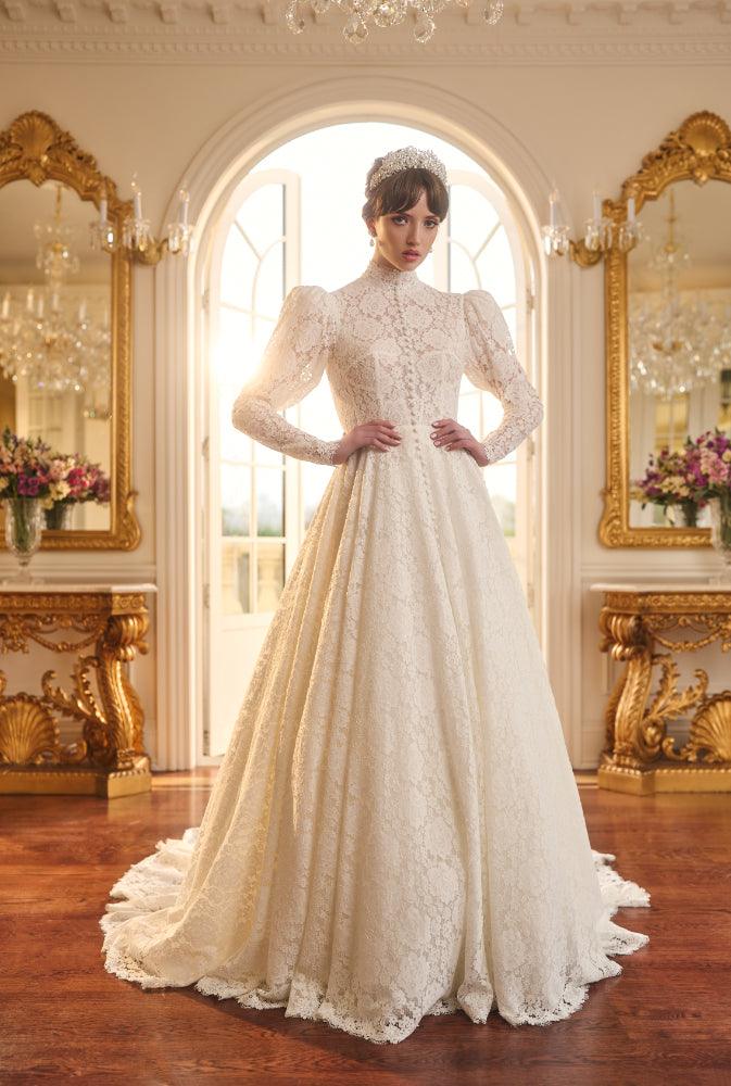 Tatyana gown in ivory lace with high neckline, mutton sleeves, and a-line skirt. Covered buttons run from neck to floor. 