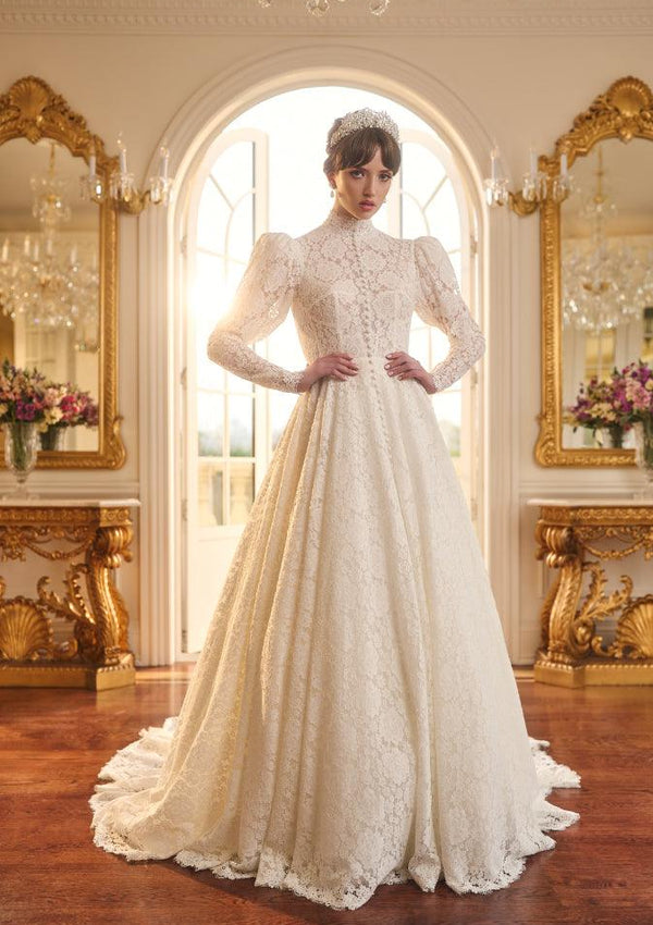 Tatyana gown in ivory lace with high neckline, mutton sleeves, and a-line skirt. Covered buttons run from neck to floor. 