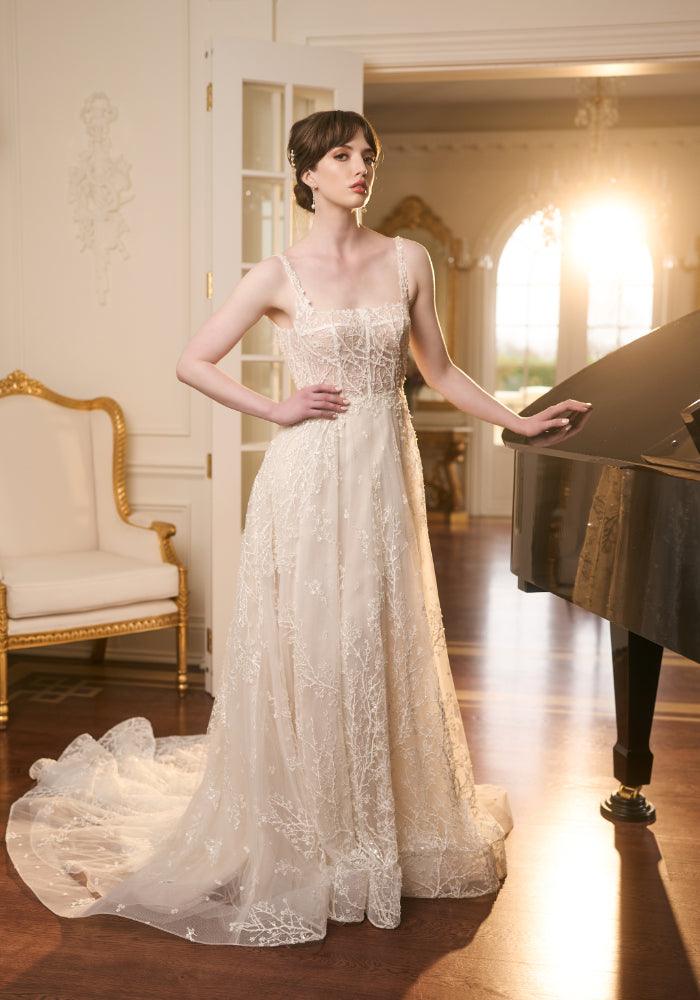 Ivory Bridal gown with sheer lace embroidered with beaded branches. Square neckline with thin straps and a-line skirt.