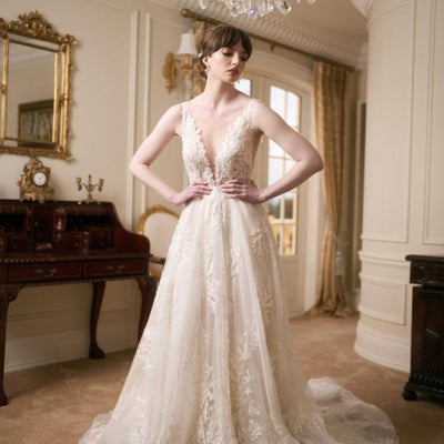 Ivory full-length wedding gown with plunging V-neckline, lace applique and a-line skirt. Embroidered with pearls and beads.