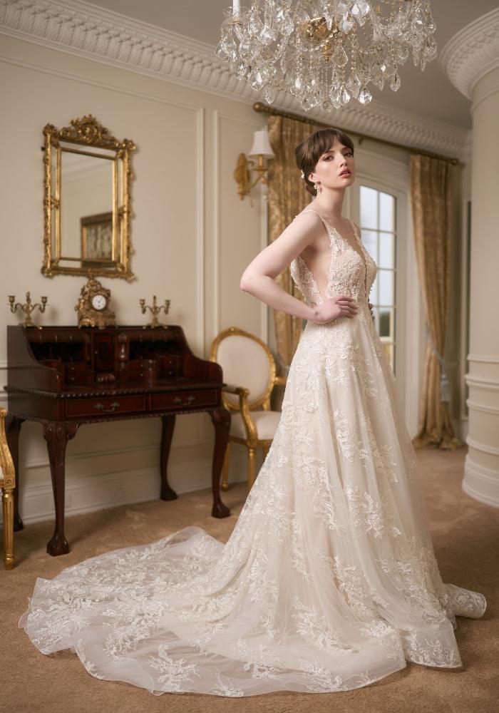 Side view of ivory full-length wedding gown with plunging V-neckline, lace applique and a-line skirt. Embroidered with pearls and beads. Illusion mesh at sides of bodice.