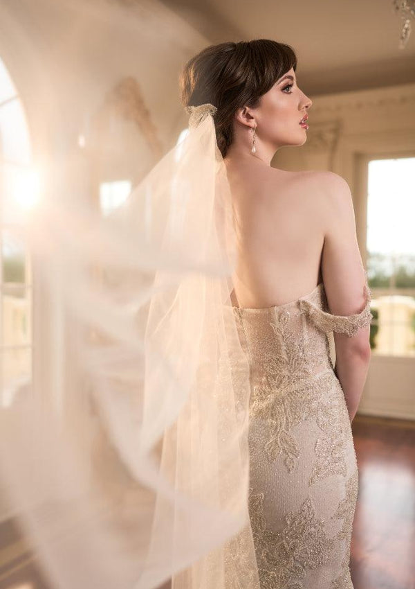 Back view of Taya dress hugging the figure with gold lace applique. Most of dress hidden by tulle veil.