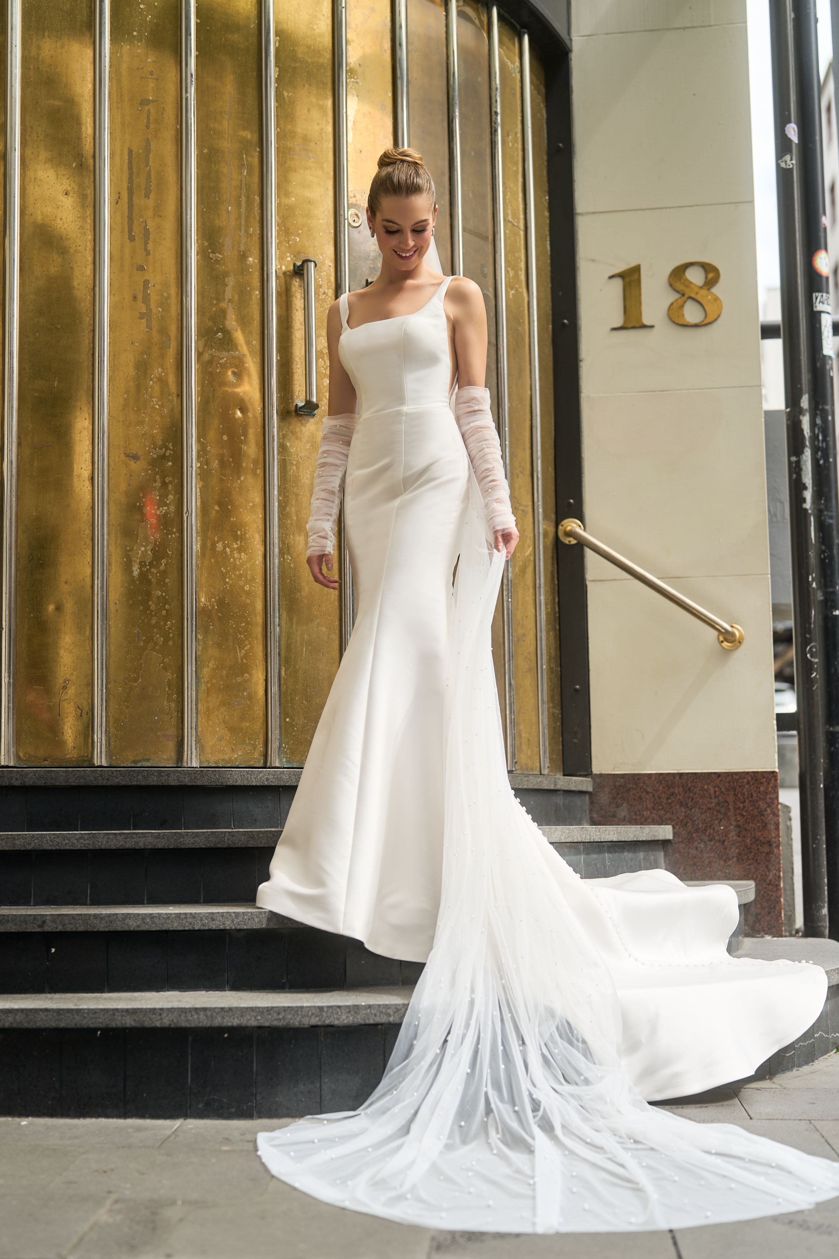 Ivory mikado minimalist gown with rouched tulle separate sleeves. Fit-n-flare shape with square neckline. Paired with 3-metre tulle veil with pearl embellishments.