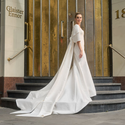 Ivory mikado minimalist gown with rouched tulle separate sleeves. Oversized bow that wraps over arms.