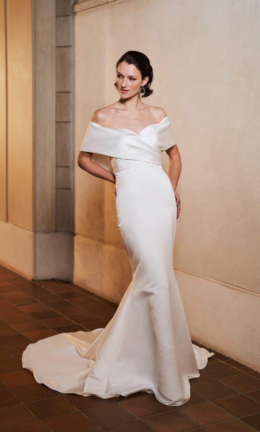 Model wearing fitted Serenity wedding dress with off shoulder sleeves from the Royal collection